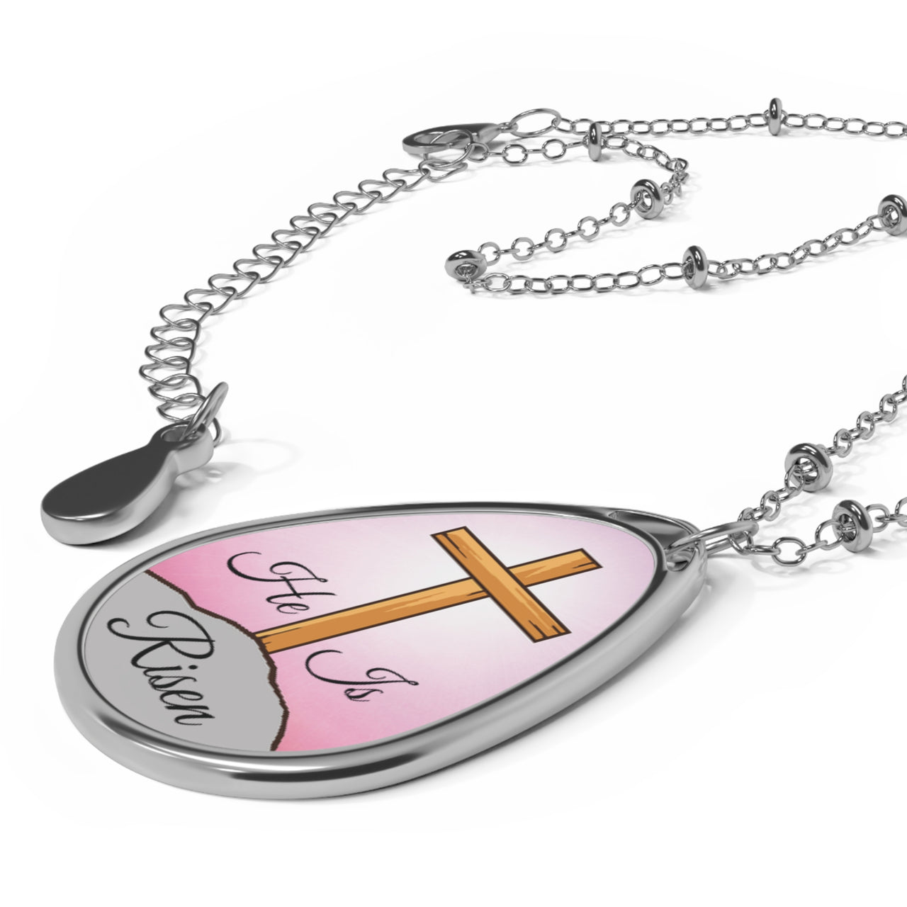 Inspirational oval pendant necklace with "He Is Risen" design,  cross on a hill artwork, zinc alloy and white aluminum, spiritual jewelry for resurrection faith, pink sky, pendant with necklace