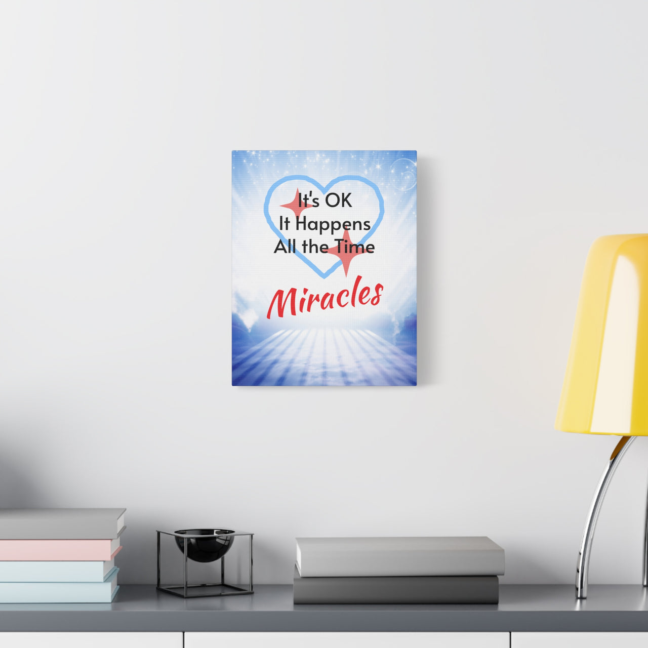 Canvas wall art with “Miracles Happen” design with the message "It's Ok, It Happens All the Time - Miracles," pinewood frame, cotton-poly blend, inspirational hope-filled message, ready to hang, 11x14 canvas wall art at desk