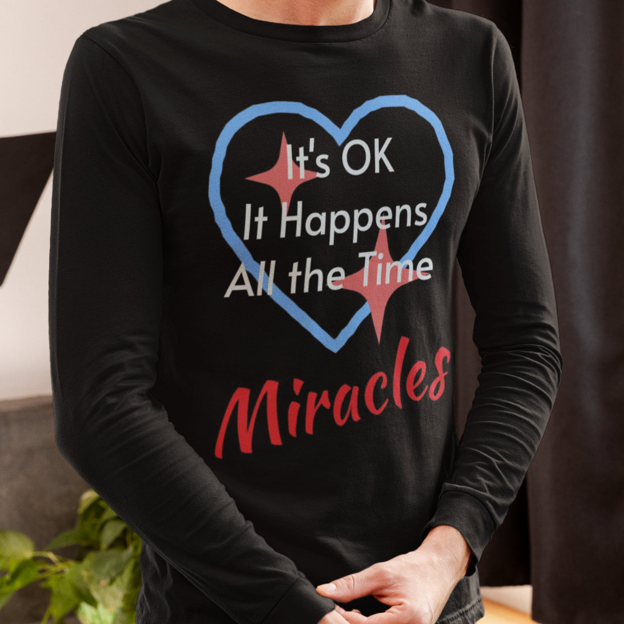 Long-sleeve Bella+Canvas t-shirt made from preshrunk ring-spun cotton with “Miracles Happen” design and message, “It’s OK. It Happens All the Time – Miracles,” faith-based apparel encouraging daily miracles through intimacy with God, man wearing long-sleeve black t-shirt