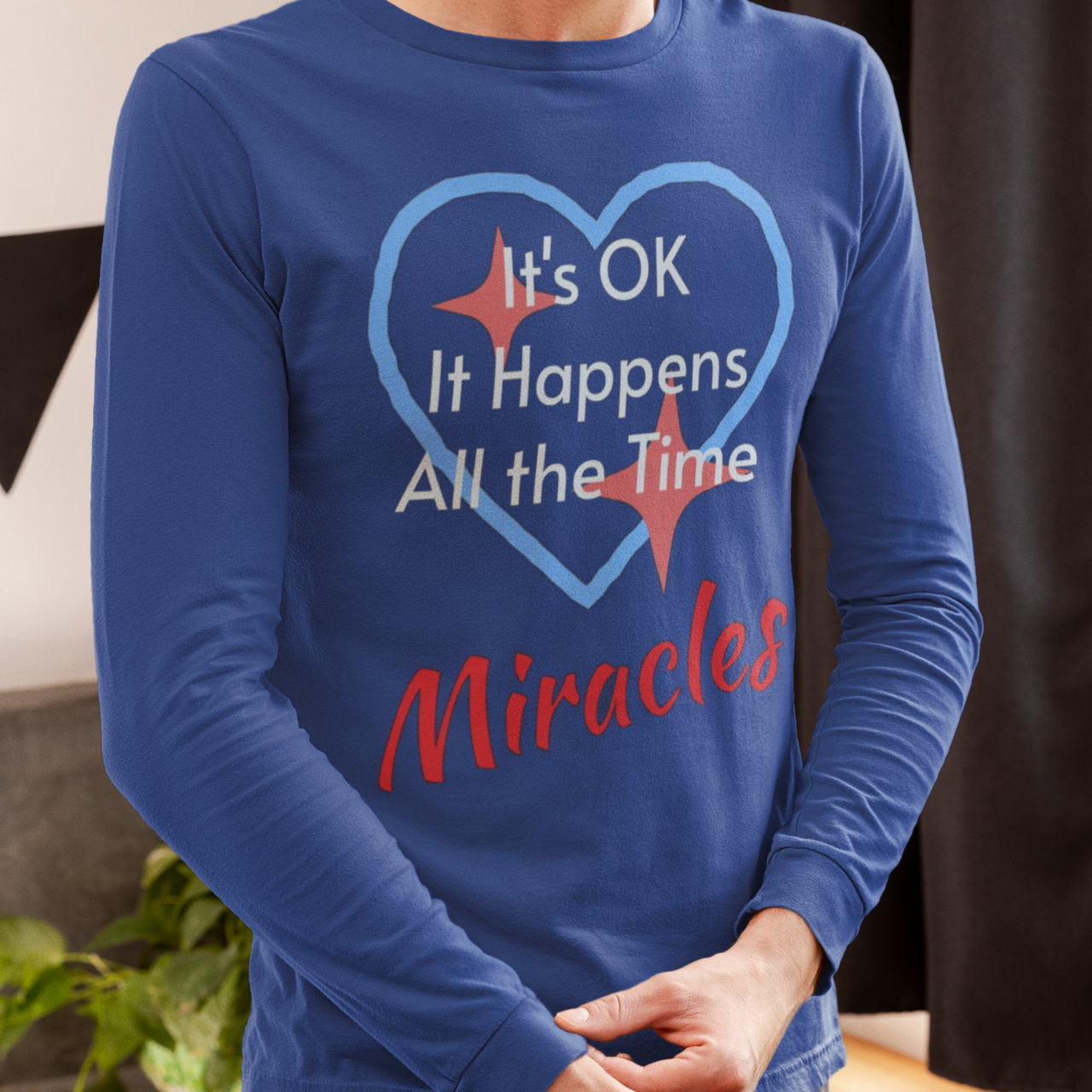 Long-sleeve Bella+Canvas t-shirt made from preshrunk ring-spun cotton with “Miracles Happen” design and message, “It’s OK. It Happens All the Time – Miracles,” faith-based apparel encouraging daily miracles through intimacy with God, man wearing long-sleeve blue t-shirt