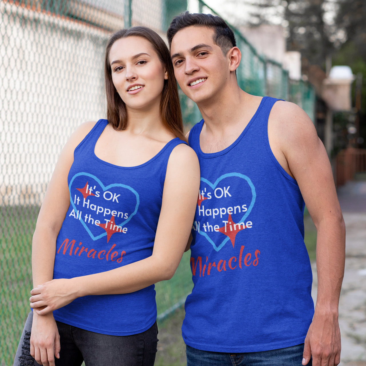 Lightweight Bella+Canvas tank top made from preshrunk cotton with “Miracles Happen” design message, “It’s OK. It Happens All the Time – Miracles,” inspirational apparel encouraging daily miracles through intimacy with God, couple wearing matching blue tank tops