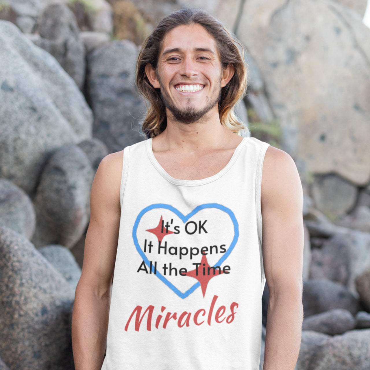 Lightweight Bella+Canvas tank top made from preshrunk cotton with “Miracles Happen” design message, “It’s OK. It Happens All the Time – Miracles,” inspirational apparel encouraging daily miracles through intimacy with God, man smiling at rock facing in white tank top