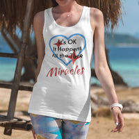 Lightweight Bella+Canvas tank top made from preshrunk cotton with “Miracles Happen” design message, “It’s OK. It Happens All the Time – Miracles,” inspirational apparel encouraging daily miracles through intimacy with God, 2nd woman at beach wearing white tank top