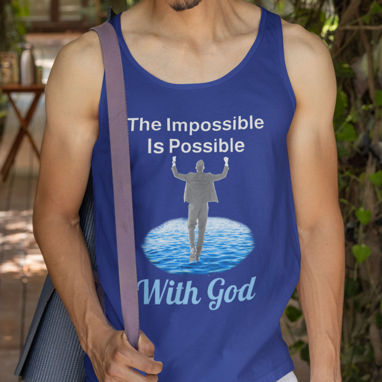 Lightweight Bella+Canvas tank top made from preshrunk cotton with “Impossible Man” design message, “The Impossible Is Possible with God,” inspirational apparel calling believers to step out in faith and walk with God into new possibilities, man wearing blue tank top