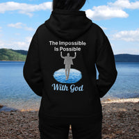Gildan unisex zip-up hoodie with “Impossible Man” design featuring a man walking on water and uplifting message, Christian apparel made from soft cotton-poly fleece, perfect for cold weather and spiritual encouragement, woman in black hoodie