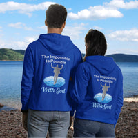 Gildan unisex zip-up hoodie with “Impossible Man” design featuring a man walking on water and uplifting message, Christian apparel made from soft cotton-poly fleece, perfect for cold weather and spiritual encouragement, couple in blue hoodie