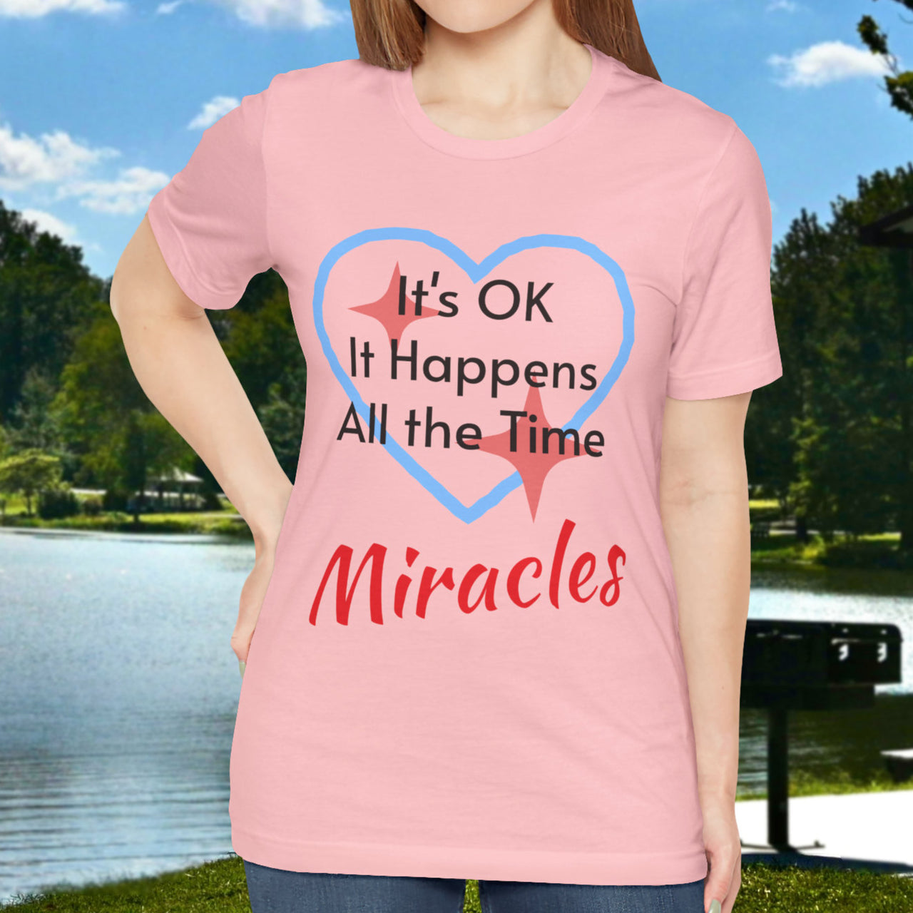 Soft, breathable Bella+Canvas t-shirt made from preshrunk cotton with “Miracles Happen” design message, “It’s OK. It Happens All the Time – Miracles,” inspirational shirt encouraging intimacy with God that produces everyday miracles, woman in pink shirt