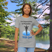 Soft, breathable Bella+Canvas t-shirt made from preshrunk cotton with “Impossible Man” design message, “The Impossible Is Possible with God,” inspirational shirt encouraging bold faith to step out and follow God into the impossible, woman in gray t-shirt at park
