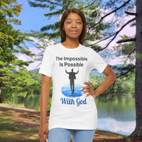 Soft, breathable Bella+Canvas t-shirt made from preshrunk cotton with “Impossible Man” design message, “The Impossible Is Possible with God,” inspirational shirt encouraging bold faith to step out and follow God into the impossible, woman in white t-shirt at park