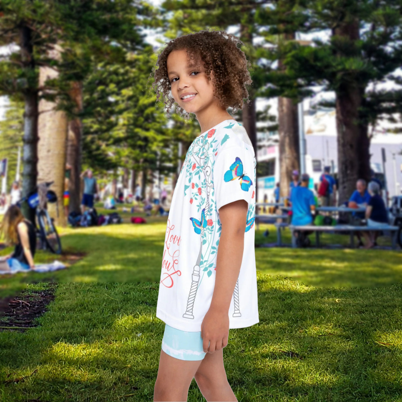 Girls’ butterfly sports jersey with colorful flower design and “I love you” message, moisture-wicking polyester, part of Paisley’s Corner Collection, ideal for school and active wear, girl in butterfly garden - left view