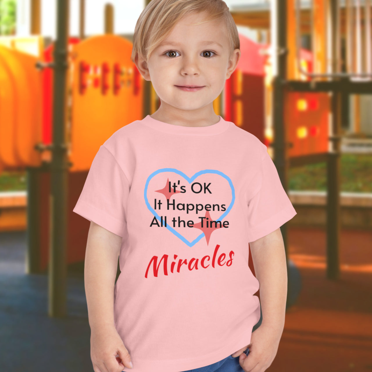 Bella+Canvas toddler t-shirt with “Miracles Happen” design and uplifting message, soft cotton, breathable and durable, Christian apparel for everyday wear and family matching, toddler boy in pink t-shirt