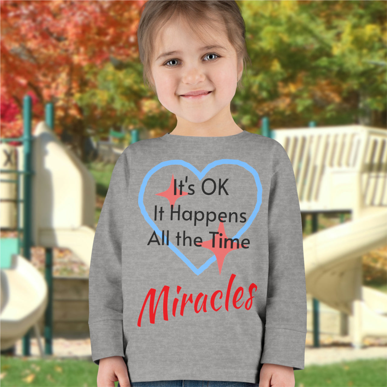 Rabbit Skins toddler long-sleeve t-shirt with “Miracles Happen” design and uplifting message, soft cotton, breathable and durable, Christian apparel for everyday wear and faith-filled gifting, todder girl in gray long-sleeve t-shirt