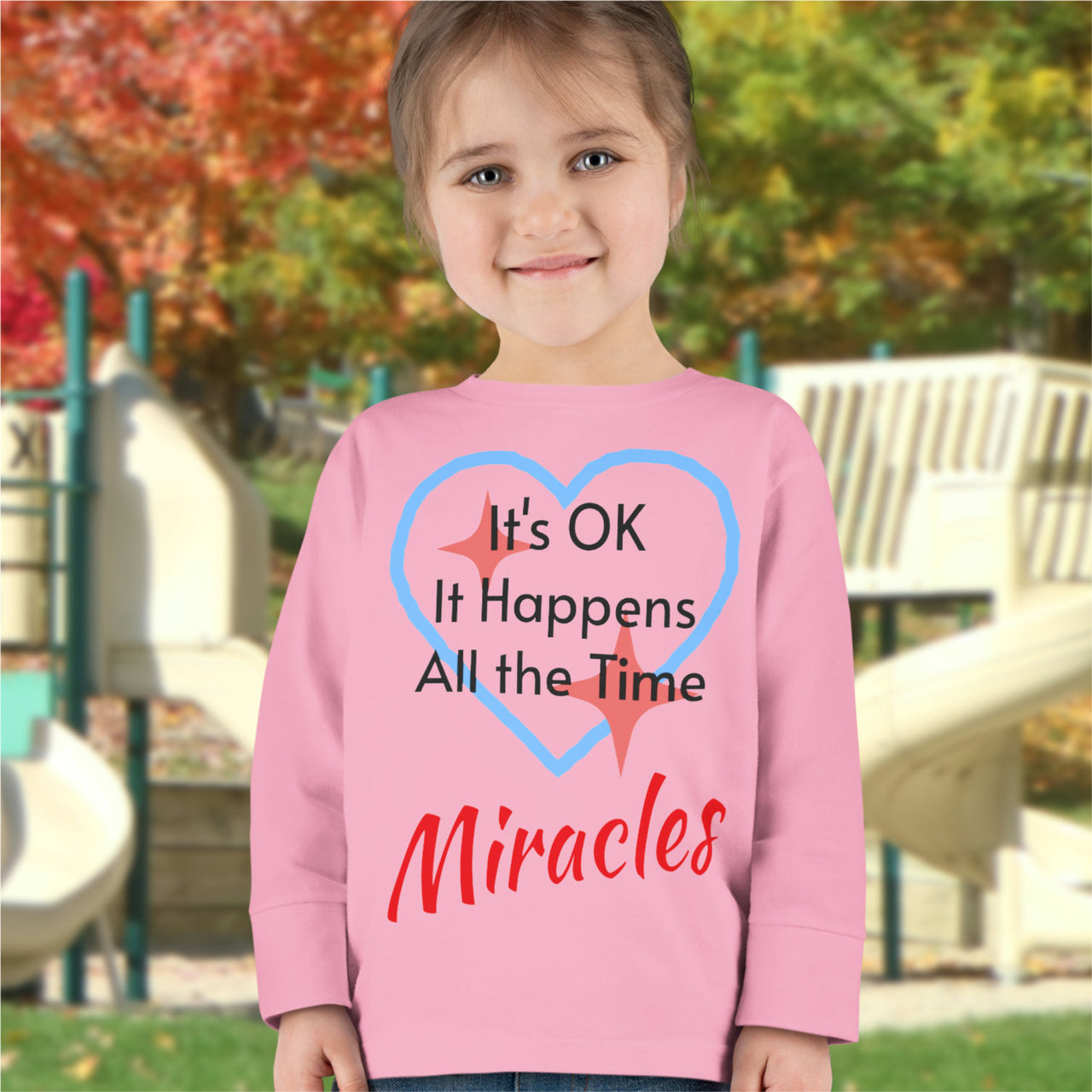 Rabbit Skins toddler long-sleeve t-shirt with “Miracles Happen” design and uplifting message, soft cotton, breathable and durable, Christian apparel for everyday wear and faith-filled gifting, todder girl in pink long-sleeve t-shirt