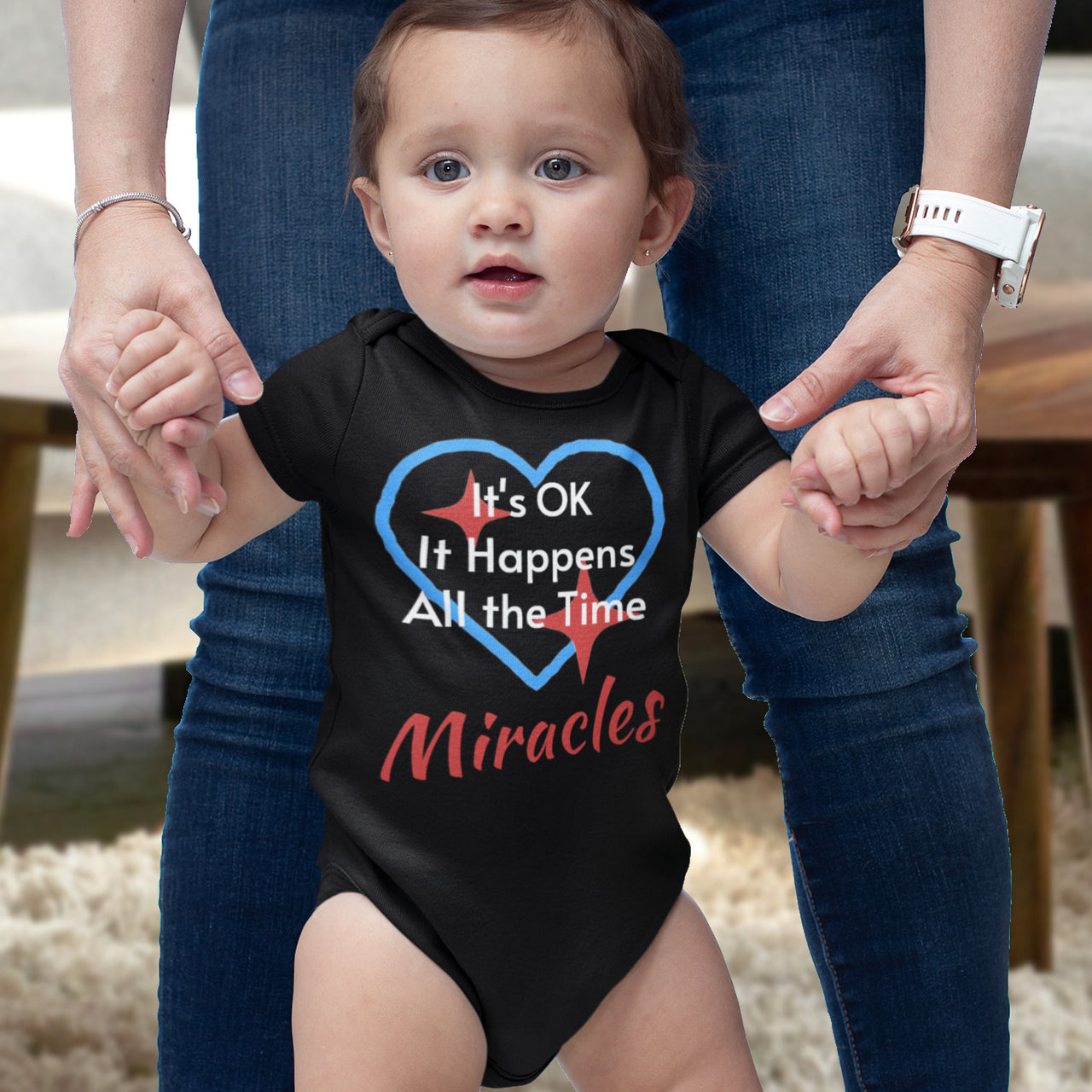 Bella+Canvas baby onesie with “Miracles Happen” design and uplifting message, soft cotton, envelope neck and snap closure, Christian apparel for infants and family matching, baby girl in black onesie