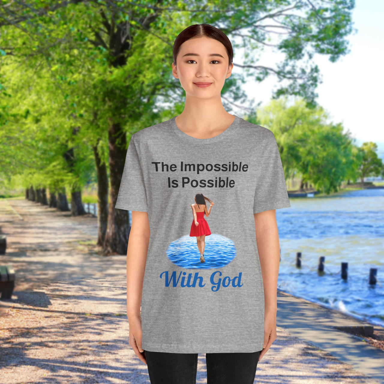 Soft, breathable Bella+Canvas t-shirt made from preshrunk cotton with “Impossible Woman” design message, “The Impossible Is Possible with God,” inspirational shirt encouraging bold obedience and faith-filled movement with God, 2nd woman in gray t-shirt at waterside walkway