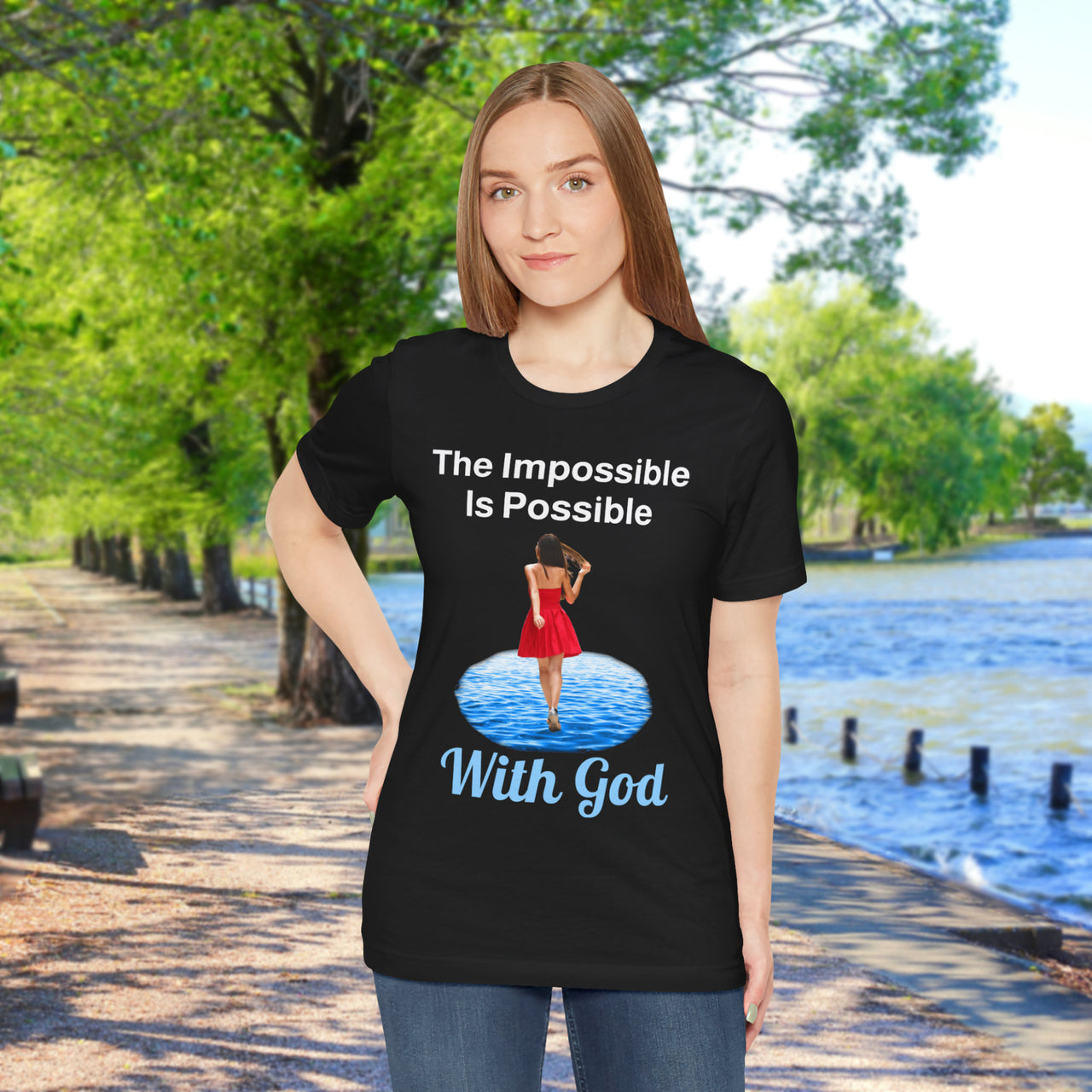 Soft, breathable Bella+Canvas t-shirt made from preshrunk cotton with “Impossible Woman” design message, “The Impossible Is Possible with God,” inspirational shirt encouraging bold obedience and faith-filled movement with God, woman in black t-shirt at waterside walkway