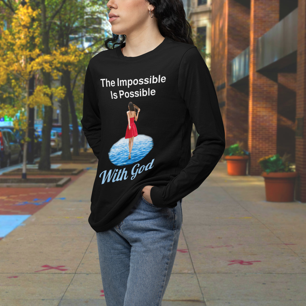 Long-sleeve Bella+Canvas t-shirt made from preshrunk ring-spun cotton with “Impossible Woman” design message, “The Impossible Is Possible with God,” inspirational apparel encouraging women to walk freely in God's incredible ways, woman downtown wearing black long-sleeve t-shirt