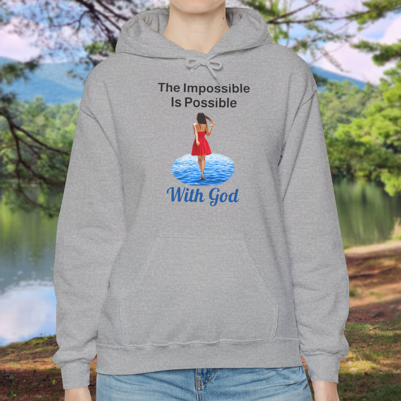 Gildan unisex hoodie with “Impossible Woman” design featuring a woman walking on water and uplifting message, Christian apparel made from soft cotton-poly blend, ideal for cold weather and faith-forward style, woman in gray hoodie