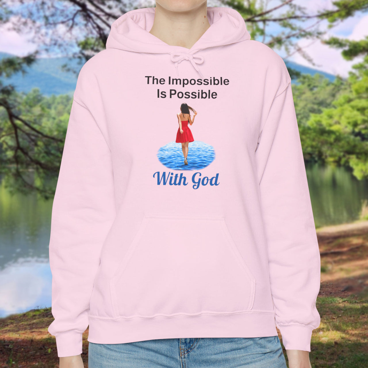 Gildan unisex hoodie with “Impossible Woman” design featuring a woman walking on water and uplifting message, Christian apparel made from soft cotton-poly blend, ideal for cold weather and faith-forward style, woman in pink hoodie