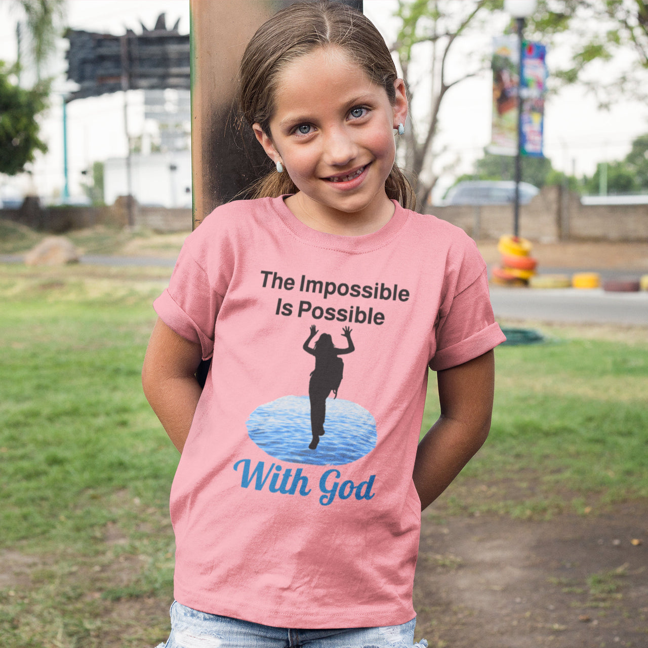 Bella+Canvas youth unisex t-shirt with “Impossible Girl” design featuring a girl walking on water and uplifting message, Christian apparel made from soft cotton, ideal for active wear and faith-forward style, young girl in pink t-shirt