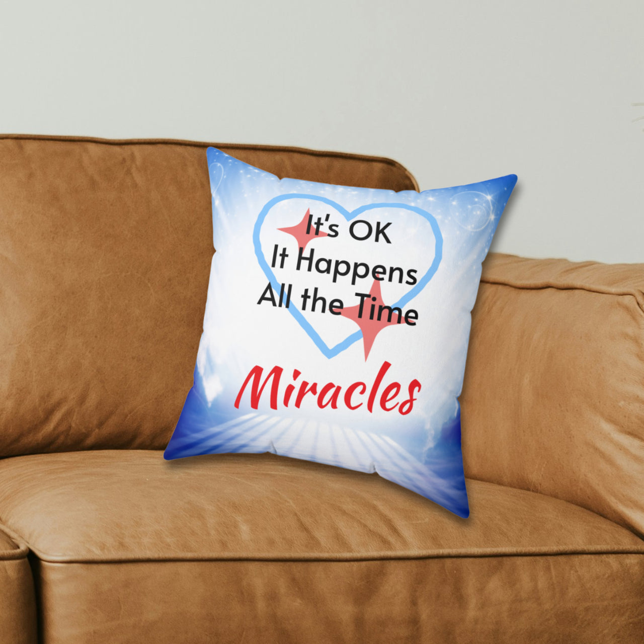 Inspirational throw pillow with “Miracles Happen” design with message "It's OK, It Happens All the Time - Miracle," reversible design, faith-based home décor, white or blue back, spun polyester, 4 sizes, 14x14 size on couch