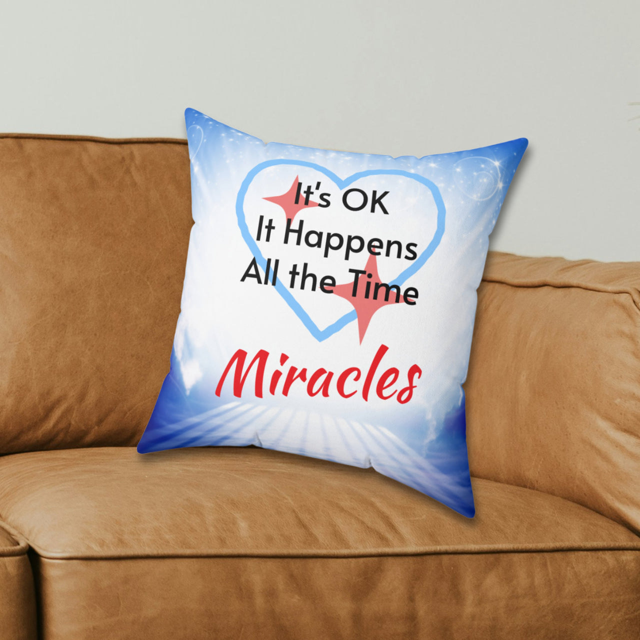 Inspirational throw pillow with “Miracles Happen” design with message "It's OK, It Happens All the Time - Miracle," reversible design, faith-based home décor, white or blue back, spun polyester, 4 sizes, 16x16 on couch