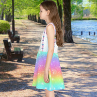 Pink girl's sundress with unicorn kitty and rainbow design, “Never Stop Dreaming” message, part of Paisley’s Treasure Chest Collection, lightweight polyester-spandex blend, ideal for summer and special occasions, left side of girl in unicorn kitty sundress
