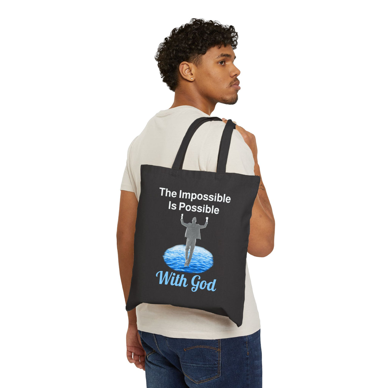 Cotton canvas tote bag with "Impossible Man" design, message “The Impossible Is Possible with God,” printed on both sides, durable spiritual tote bag for men walking in faith, man carrying black tote bag