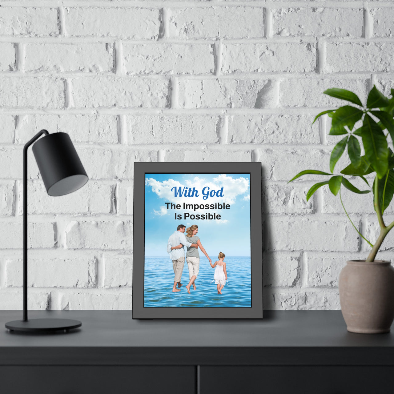 Black wood framed inspirational poster with “Impossible Family” design, family walking on water with the message "With God, The Impossible Is Possible," semi-gloss finish, shatter-proof plexiglass, available in 3 sizes, 11x14 framed poster at desk