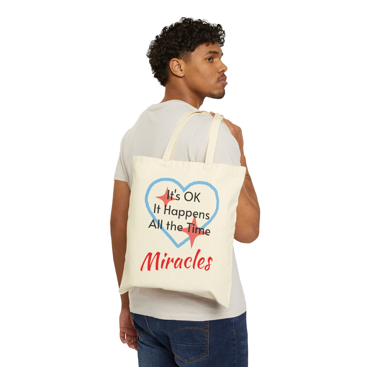 Cotton canvas tote bag with "Miracles Happen" design, message “It’s OK. It Happens All the Time – Miracles,” printed on both sides, durable faith-based tote bag for everyday encouragement of God's goodness, man carrying natural tote bag