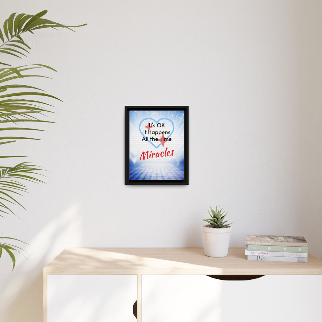 Framed canvas wall art with “Miracles Happen” design, inspirational message "It's OK, It Happens All the Time - Miracles," black pinewood frame, coated cotton-poly canvas, ready to hang, 11x14 framed wall art at desk