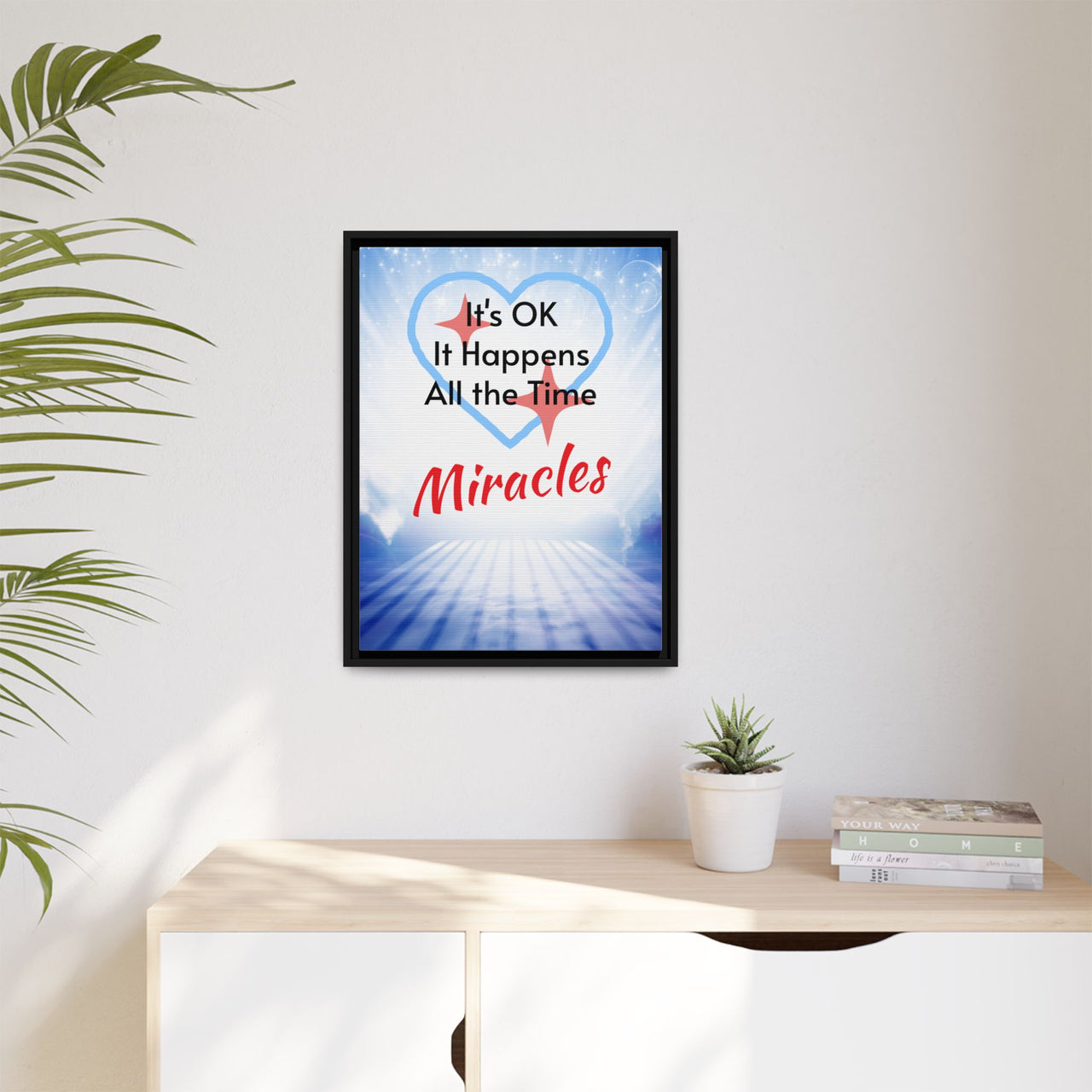 Framed canvas wall art with “Miracles Happen” design, inspirational message "It's OK, It Happens All the Time - Miracles," black pinewood frame, coated cotton-poly canvas, ready to hang, 18x24 framed wall art on wall