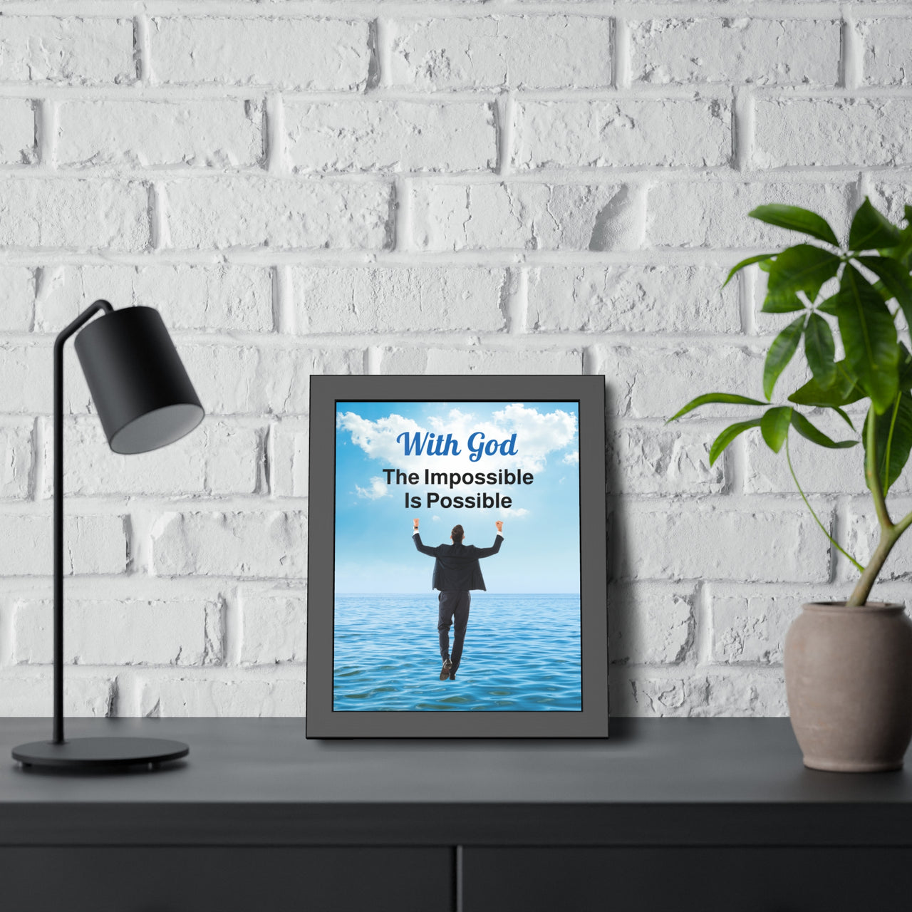 Black wood framed inspirational poster with “Impossible Man” design, man walking on water with the message "With God, The Impossible Is Possible," semi-gloss finish, shatter-proof plexiglass, available in 3 sizes, 11x14 framed poster at desk