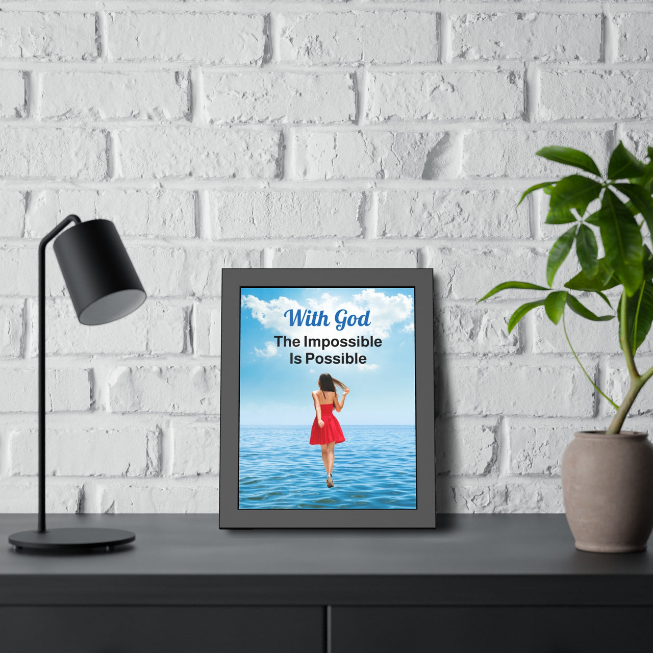 Black wood framed inspirational poster with “Impossible Woman” design, woman walking on water with the message "With God, The Impossible Is Possible," semi-gloss finish, shatter-proof plexiglass, available in 3 sizes, 11x14 poster at desk
