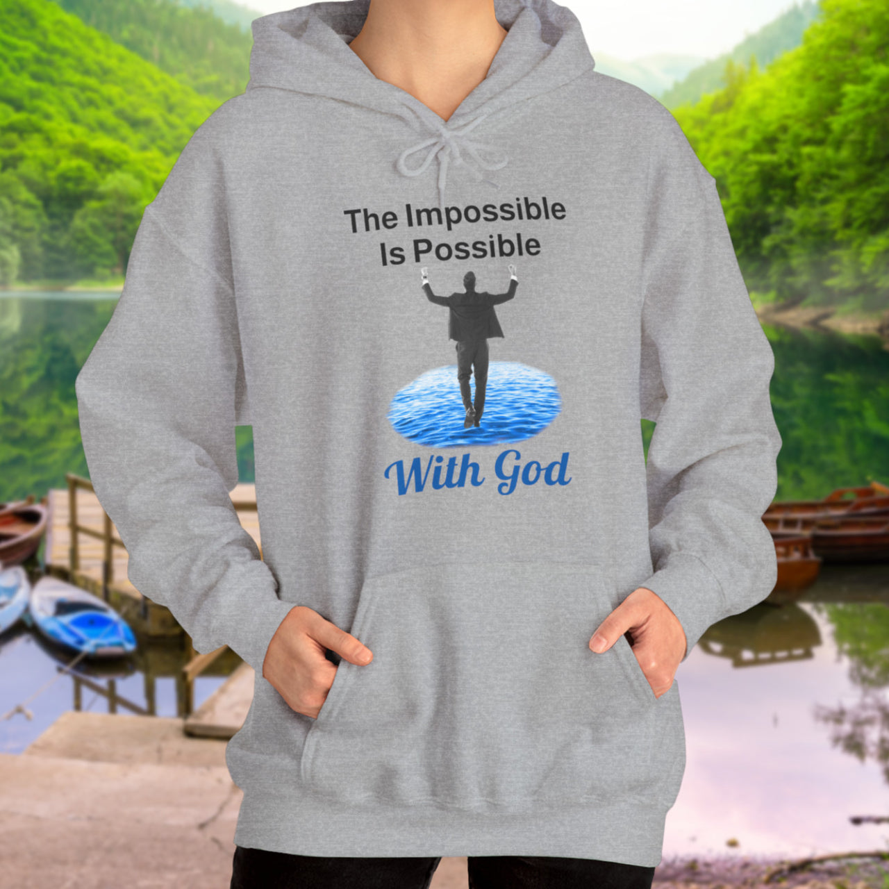 Gildan unisex hoodie with “Impossible Man” design featuring a man walking on water and uplifting message, Christian apparel made from soft cotton-poly blend, perfect for cold weather and spiritual encouragement, woman in gray hoodie