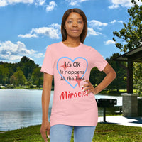 Soft, breathable Bella+Canvas t-shirt made from preshrunk cotton with “Miracles Happen” design message, “It’s OK. It Happens All the Time – Miracles,” inspirational shirt encouraging intimacy with God that produces everyday miracles, 2nd woman in pink at lakeside park
