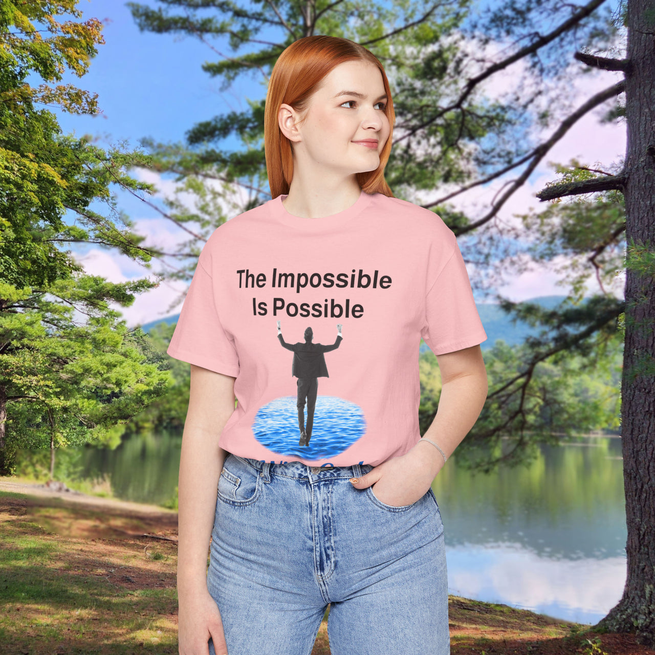 Soft, breathable Bella+Canvas t-shirt made from preshrunk cotton with “Impossible Man” design message, “The Impossible Is Possible with God,” inspirational shirt encouraging bold faith to step out and follow God into the impossible, 2nd woman in pink t-shirt at park