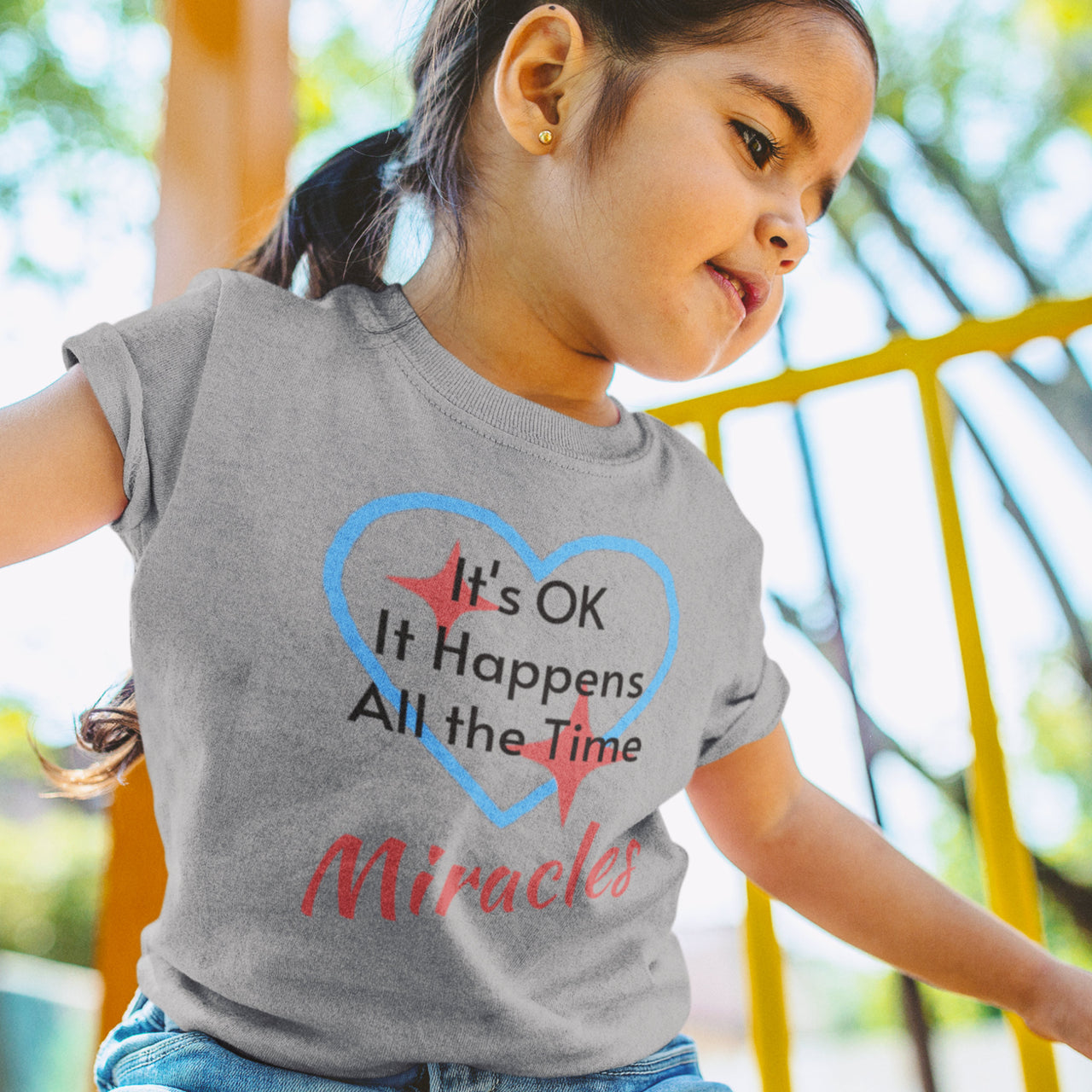 Bella+Canvas toddler t-shirt with “Miracles Happen” design and uplifting message, soft cotton, breathable and durable, Christian apparel for everyday wear and family matching, toddler girl in gray t-shirt
