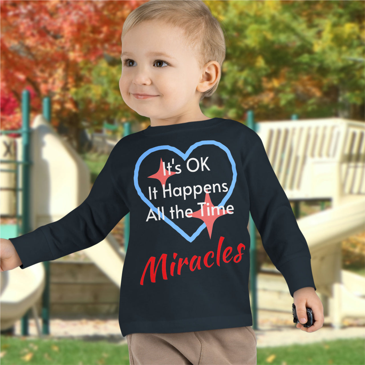 Rabbit Skins toddler long-sleeve t-shirt with “Miracles Happen” design and uplifting message, soft cotton, breathable and durable, Christian apparel for everyday wear and faith-filled gifting, todder boy in black long-sleeve t-shirt
