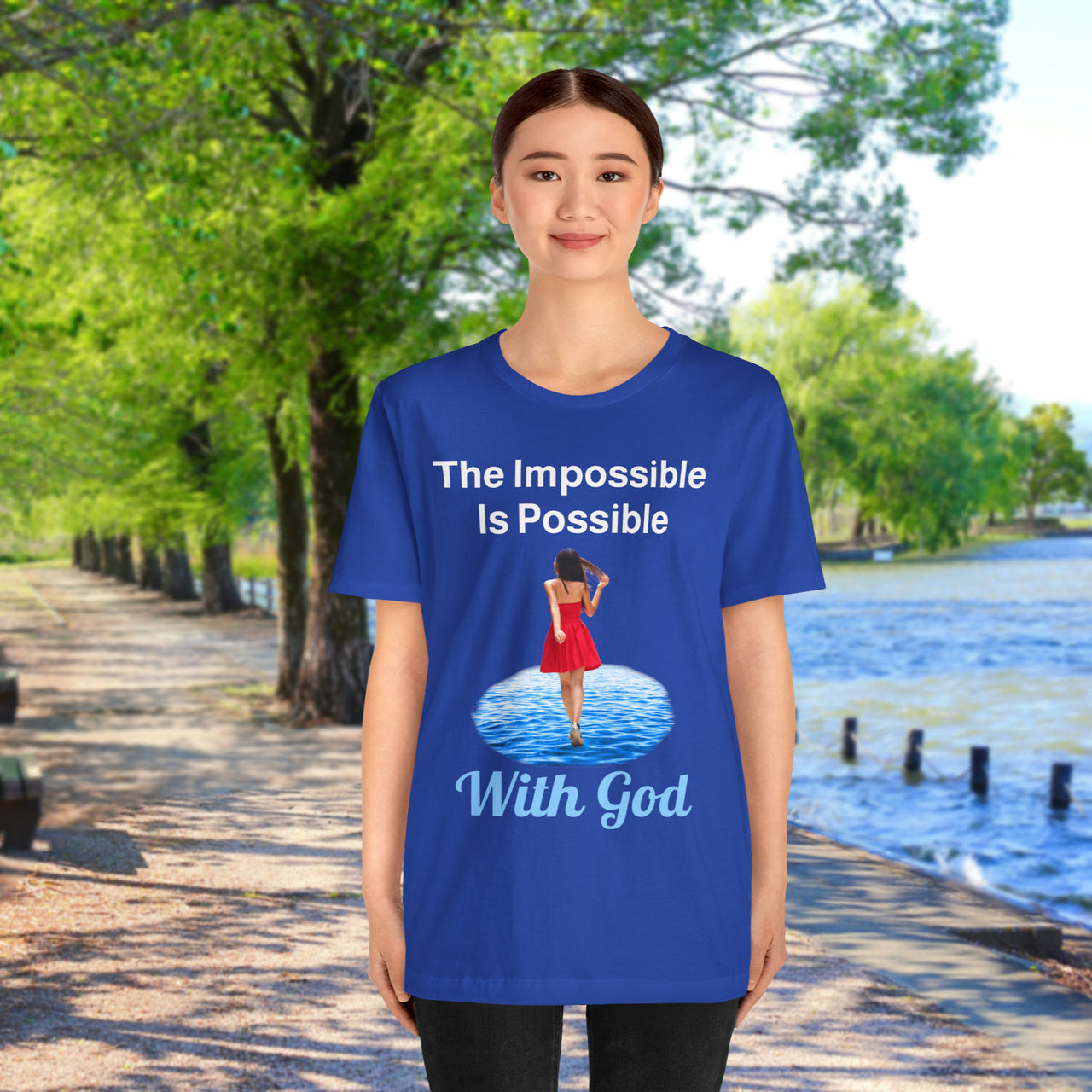 Soft, breathable Bella+Canvas t-shirt made from preshrunk cotton with “Impossible Woman” design message, “The Impossible Is Possible with God,” inspirational shirt encouraging bold obedience and faith-filled movement with God, 2nd woman in blue t-shirt at waterside walkway