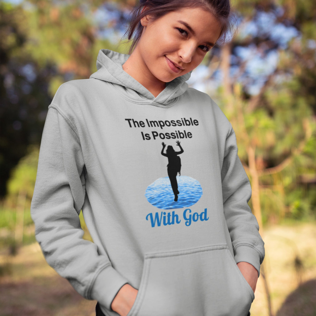 Gildan youth unisex hoodie with “Impossible Girl” design featuring a girl walking on water and uplifting message, Christian apparel made from soft preshrunk fleece, ideal for cooler weather and faith-forward style, teen girl in gray hoodie