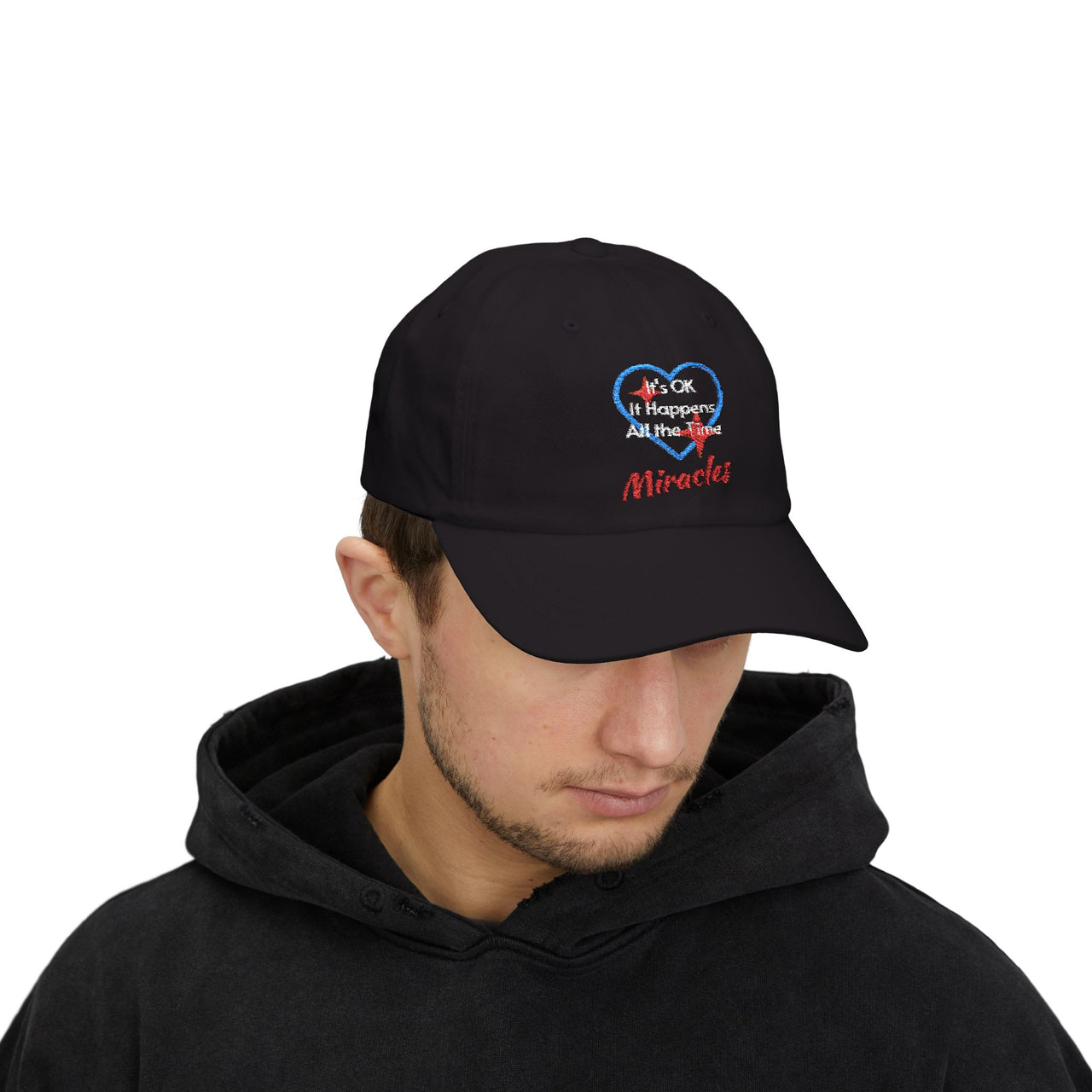 Classic cotton baseball cap with "Miracles Happen" design, message “It’s OK. It Happens All the Time – Miracles,” adjustable fit, spiritual hat for everyday encouragement, man wearing black cap