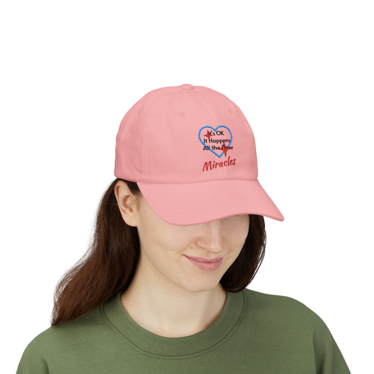 Classic cotton baseball cap with "Miracles Happen" design, message “It’s OK. It Happens All the Time – Miracles,” adjustable fit, spiritual hat for everyday encouragement, woman wearing pink cap