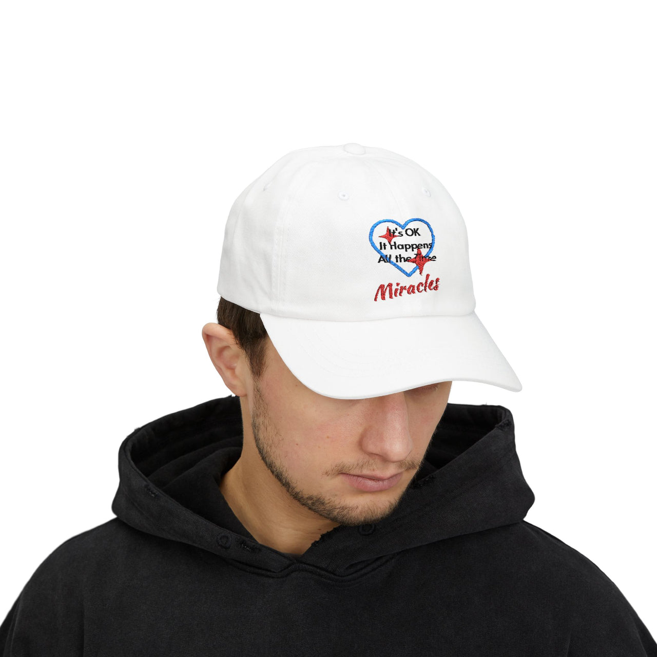 Classic cotton baseball cap with "Miracles Happen" design, message “It’s OK. It Happens All the Time – Miracles,” adjustable fit, spiritual hat for everyday encouragement, man wearing white cap